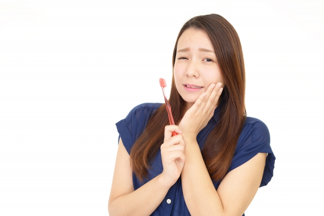 虫歯が痛くて、頬に手を当てている女性